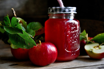 Stewed apples on a rustic table in a glass with a straw and apples.