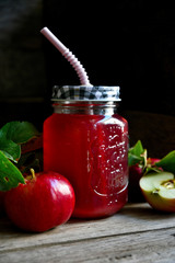 Stewed apples on a rustic table in a glass with a straw and apples.