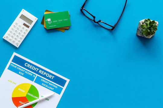 credit report with credit cards and calculator, glasses on banker work place blue background top view mock up