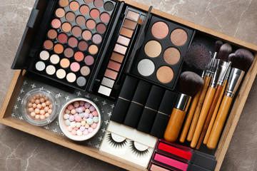 Set of different professional makeup products in box on table, top view