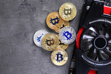 Bitcoins and video card on grey background, space for text