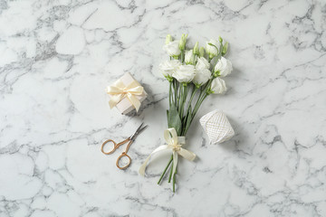 Flat lay composition with scissors and flowers on white marble background