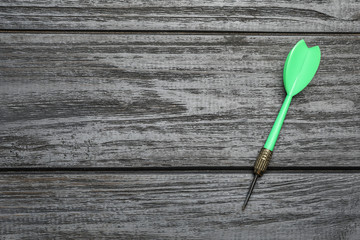 Green dart arrow on grey wooden table, top view with space for text