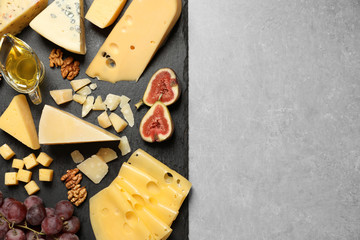 Different delicious cheeses served on grey table, top view. Space for text