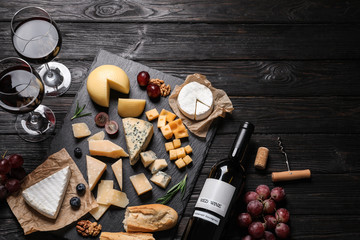 Different types of delicious cheese served on black wooden table, top view