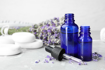 Bottles with natural lavender essential oil on table, space for text