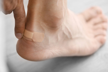 Man applying adhesive bandage on heel indoors, closeup