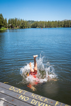 Boy jumping into beautiful blue lake