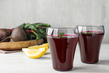 Glasses of beet juice on white wooden table. Space for text