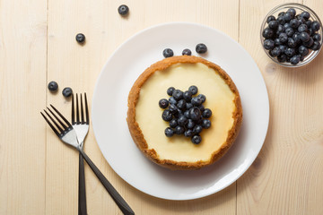 Plate with delicious cheesecake and two forks on wooden table.