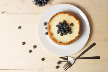 Plate with delicious cheesecake and two forks on wooden table.