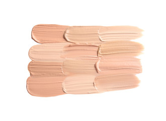 Samples of different foundation shades on white background, top view