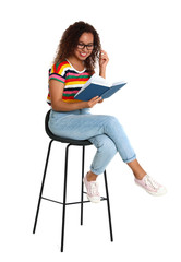 Beautiful African-American woman reading book on white background