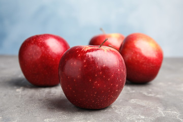 Ripe juicy red apples on grey table against blue background