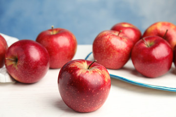 Ripe juicy red apples on white wooden table against blue background