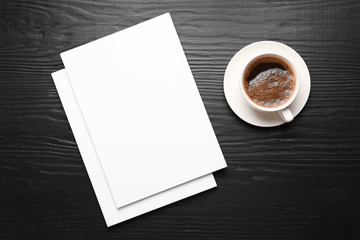Obraz na płótnie Canvas Blank paper sheets for brochure and cup of coffee on black wooden background, flat lay. Mock up