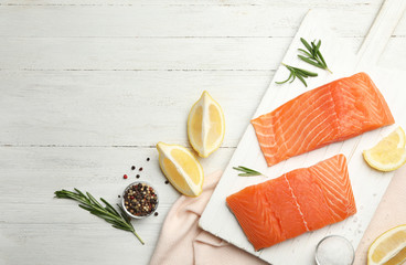 Flat lay composition with salmon fillet on white wooden table. Space for text