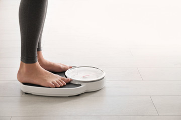 Woman standing on scales indoors, space for text. Overweight problem - obrazy, fototapety, plakaty
