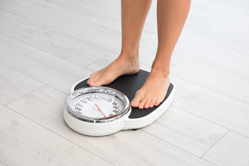 Woman standing on scales indoors. Overweight problem