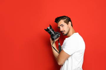 Fototapeta na wymiar Young photographer with professional camera on red background. Space for text
