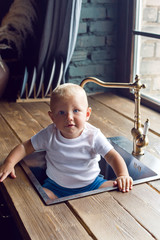 child in a white t-shirt sitting in the kitchen sink