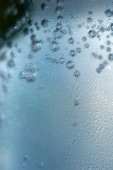 Macro shot of bubbles in a soda. Water drops on a cold transparent glass.