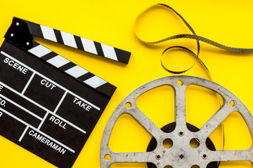 Filmmaker profession with clapperboard and video tape on yellow background top view