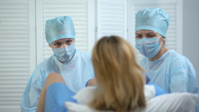 Obstetricians assisting woman pushing to give child birth, maternity ward