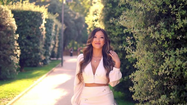 Beautiful Asian girl smiling in the park. She is wearing white dress. Happy video