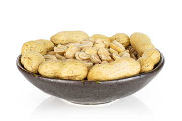 Lot of whole lot of halves of natural yellow peanut in dark ceramic bowl isolated on white background