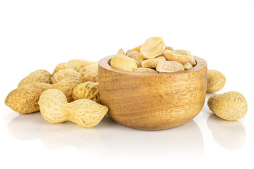 Lot of whole lot of halves of natural yellow peanut in tiny wooden bowl isolated on white background