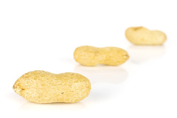 Group of three whole natural yellow peanut placed diagonally in line isolated on white background