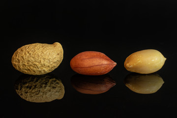 Group of three whole natural yellow peanut in row isolated on black glass