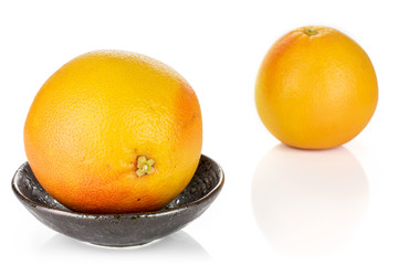 Group of two whole fresh pink grapefruit in dark ceramic bowl isolated on white background