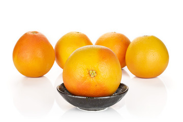 Group of five whole fresh pink grapefruit arranged symmetrically in dark ceramic bowl isolated on white background