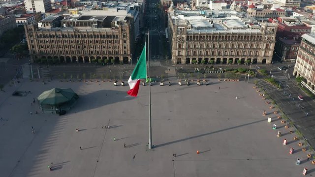 day view of Mexican flag in center of Zocalo flying backward over National Cathedral