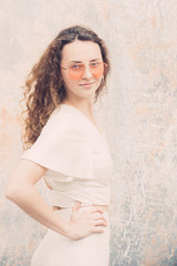 Millenial trendy Hipster teenager enjoys and relaxes during a walk in city center, she has orange lens sunglasses and white minimalistic dress, portraiture series,
