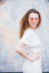 Millenial trendy Hipster teenager enjoys and relaxes during a walk in city center, she has orange lens sunglasses and white minimalistic dress, portraiture series,