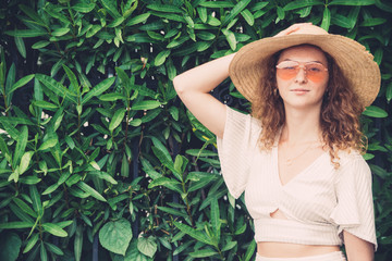 Millenial trendy Hipster teenager poses in front a green background  she has orange lens glasses and white minimalistic dress, portraiture series, retro style tones color