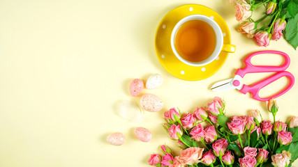 Obraz na płótnie Canvas Welcoming Spring pink and yellow theme concept flat lay tea break with roses and gardening accessories.
