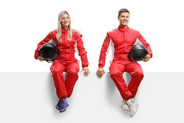 Male and female car racers sitting on panel in red uniforms