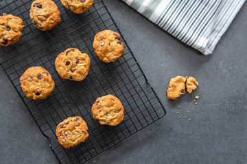 Freshly baked homemade chocolate chip cookies on wire rack with dark background, flat lay