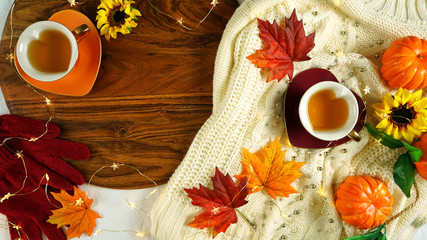 Autumn Fall theme flatlay overhead with cosy sweater, bagels, cups of herbal tea and scattered maple leaves.