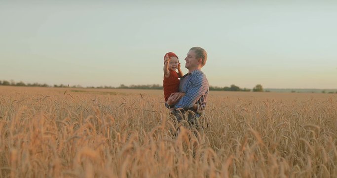 Happy baby sitting with dad in his arms, a walk in the field. Endless open spaces of the field.