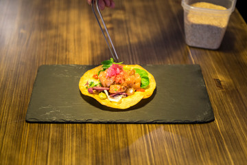 chef finishing preparing a taco with meat tartare