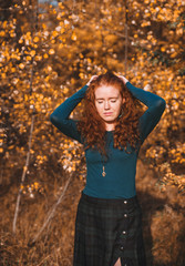 Beautiful red haired woman on autumn background.