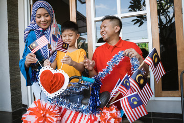 happy malaysian family decorate bicycle with flag for independence day celebration. malaysia merdeka basikal hias