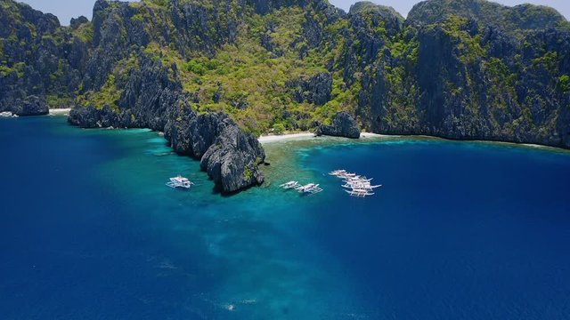 Aerial hover view of trip boats moored on diving spot near secret lagoon on Miniloc Island. El-Nido, Palawan. Philippines