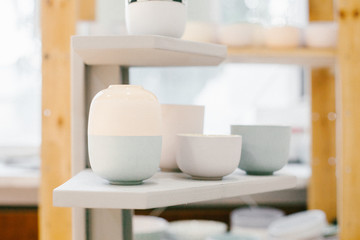 Set of multicoloured ceramic minimalistic vase and cups on soft  background.