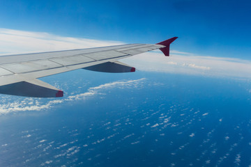 Naklejka na ściany i meble Airplane wing with blue sky and ocean background